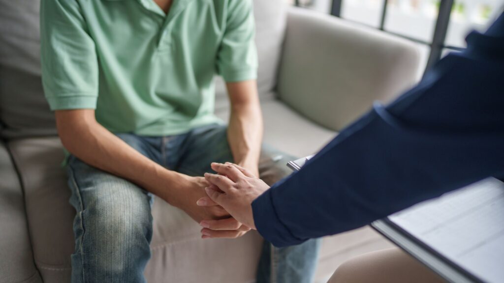 Person showing support by placing hand on peer's hand
