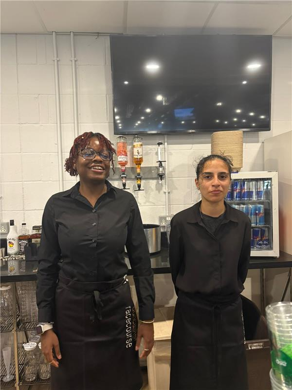 Two women stood behind a bar ready to work